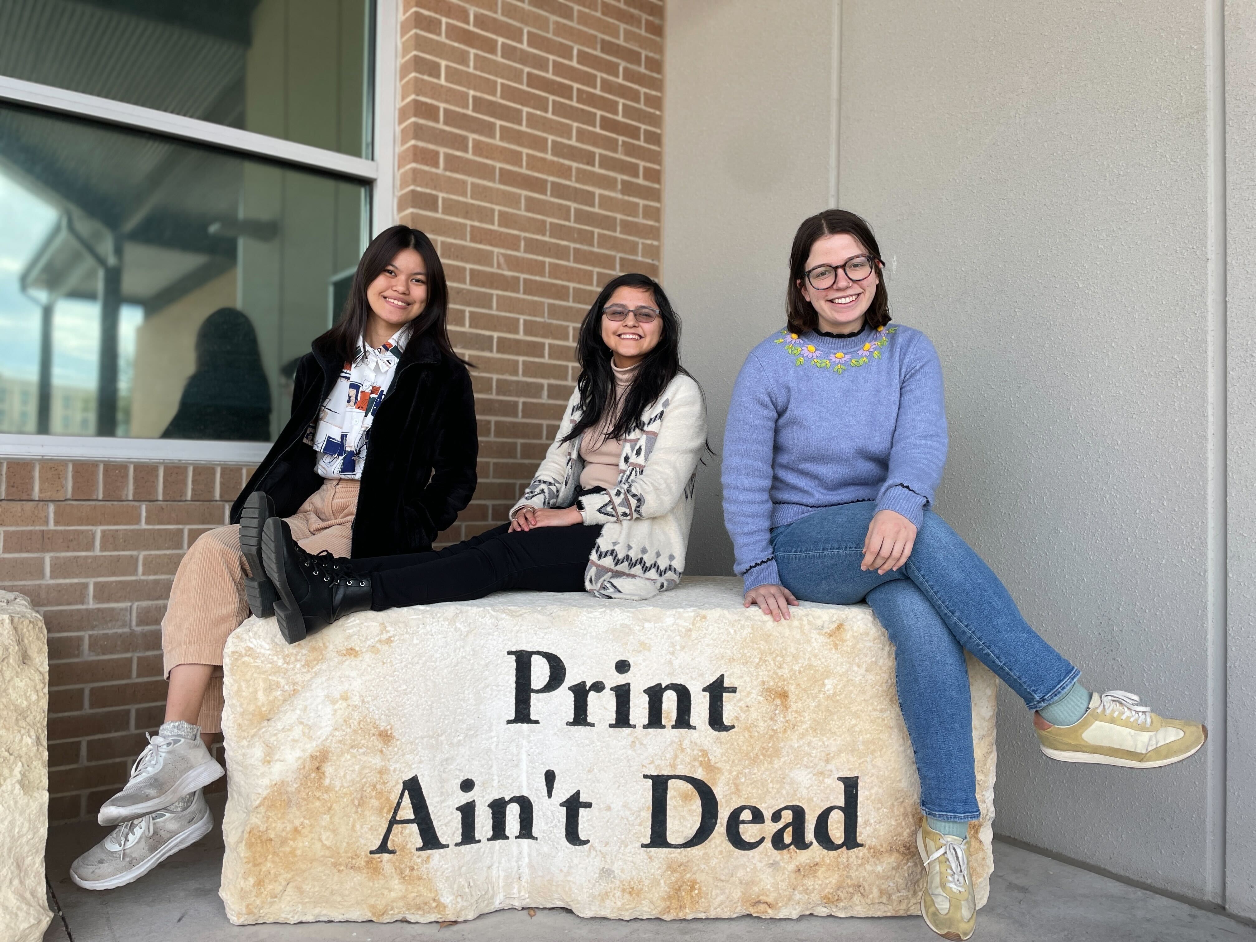 students on stone that says print aint dead