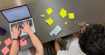 students working on computer with sticky notes