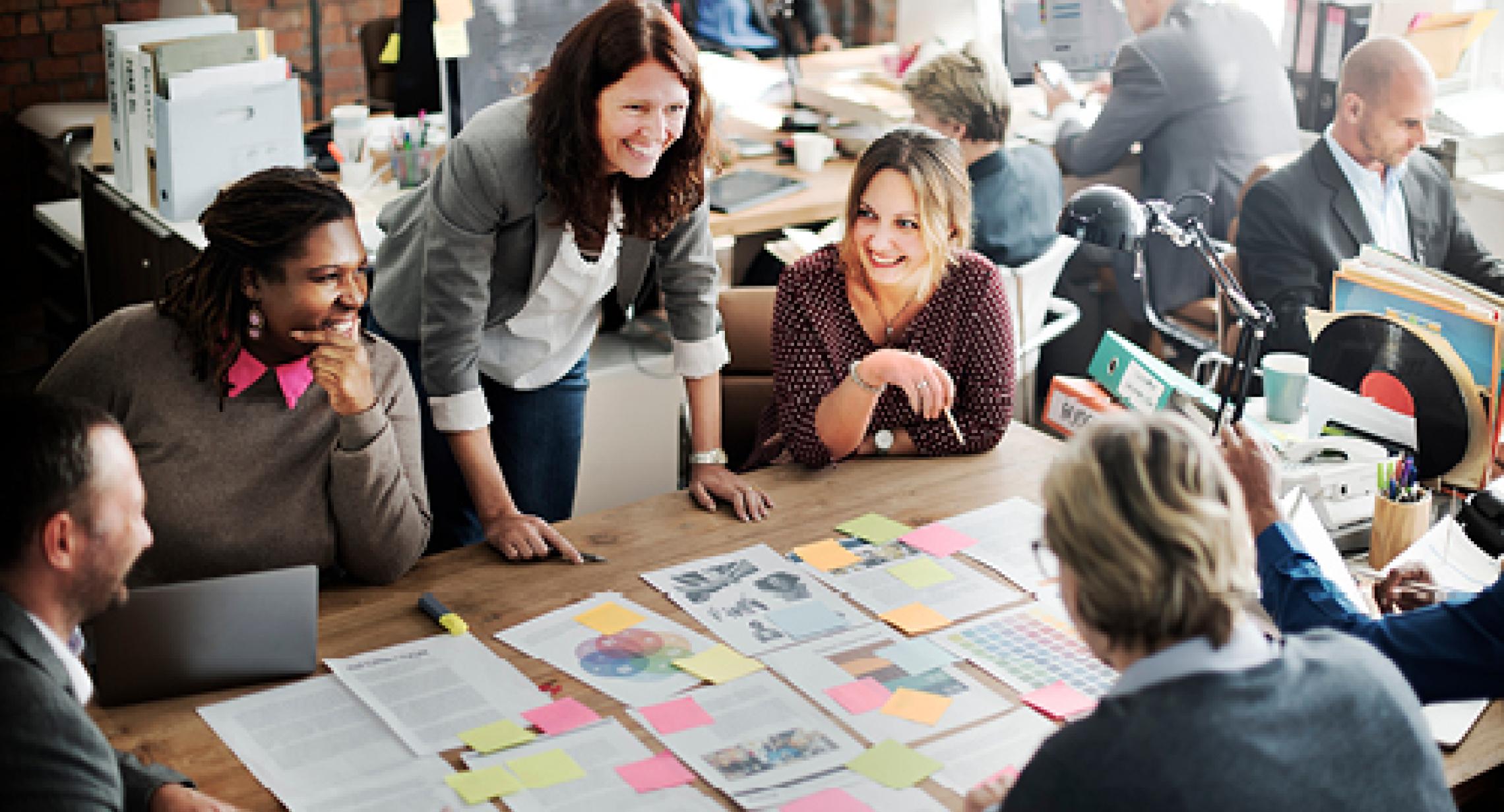 Group of people at work, collaborating over paper documents