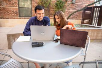 Ashley Miznazi and Kenny Jones work on their podcast at a patio table.